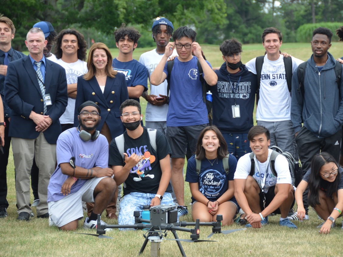 group of diverse people posing with a drone