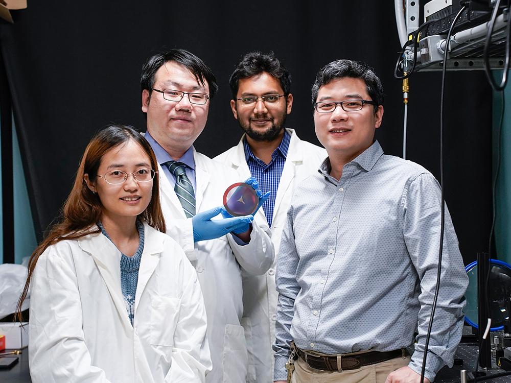 Penn State electrical engineering graduate students (from left) Lidan Zhang, Shengyuan Chang, Md Tarek Rahman and Penn State Associate Professor of Electrical Engineering Xingjie Ni display their flat, compact metalens, which when integrated into a telescope, can image the lunar surface. Credit: Jeff Xu/Penn State.