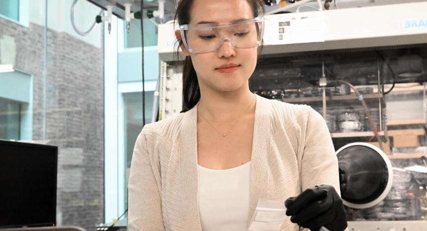 Young woman looking at a battery coin cell in a lab