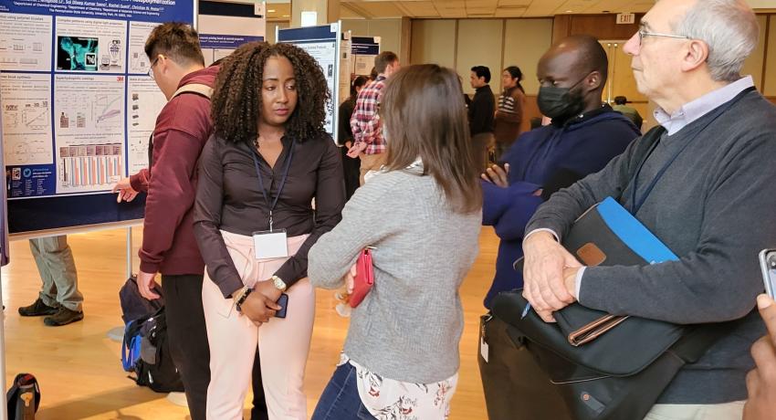 People viewing a poster during a research poster session in a large room