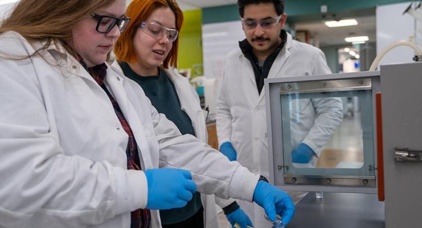 Man and two women in a lab readying a sample of cellulose