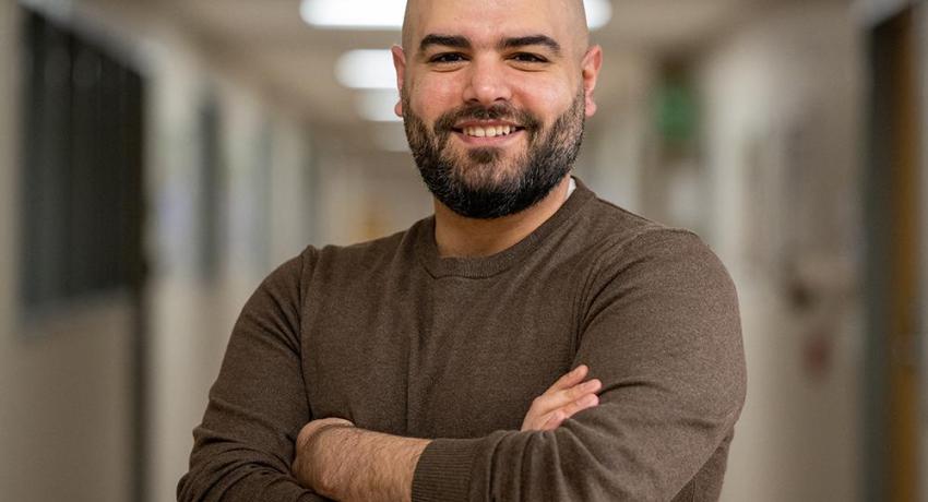 man in hallway standing with his arms crossed and smiling