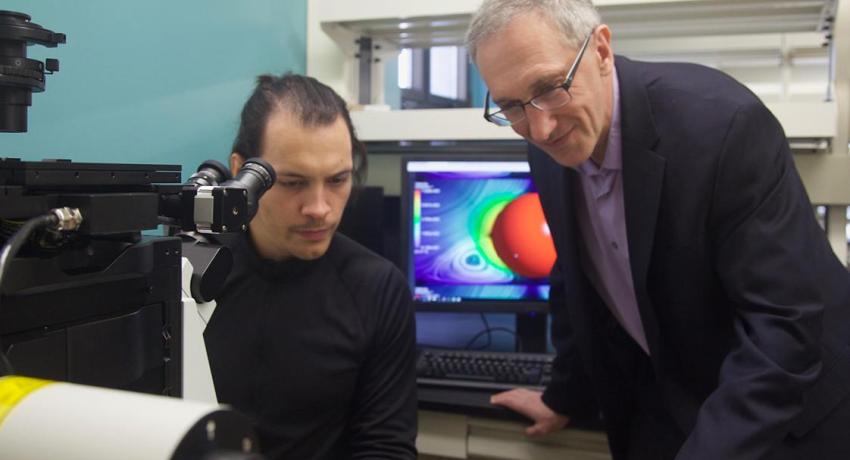 two men reviewing research findings on a laptop in a lab.